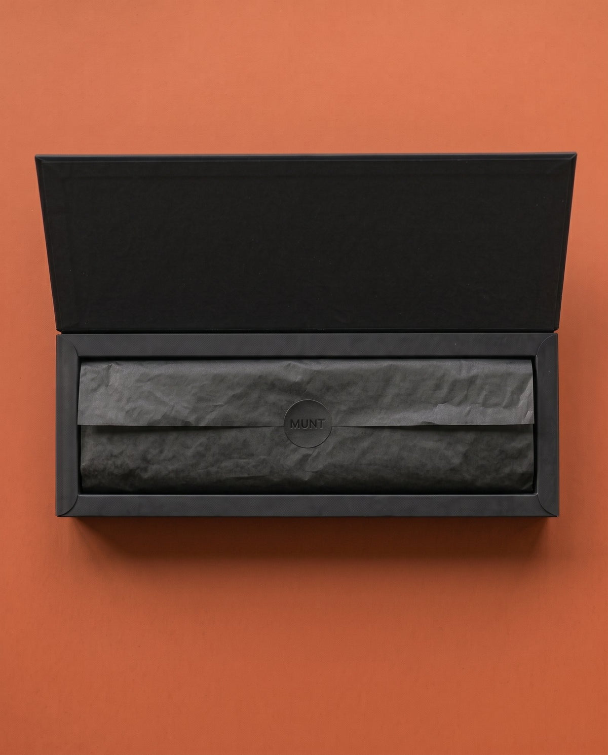 The lid opening further, black tissue inside.